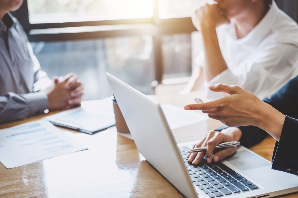 Réunion de travail autour d’un ordinateur portable, illustrant la coopération et la coordination du comité de pilotage du Groupe Novances.