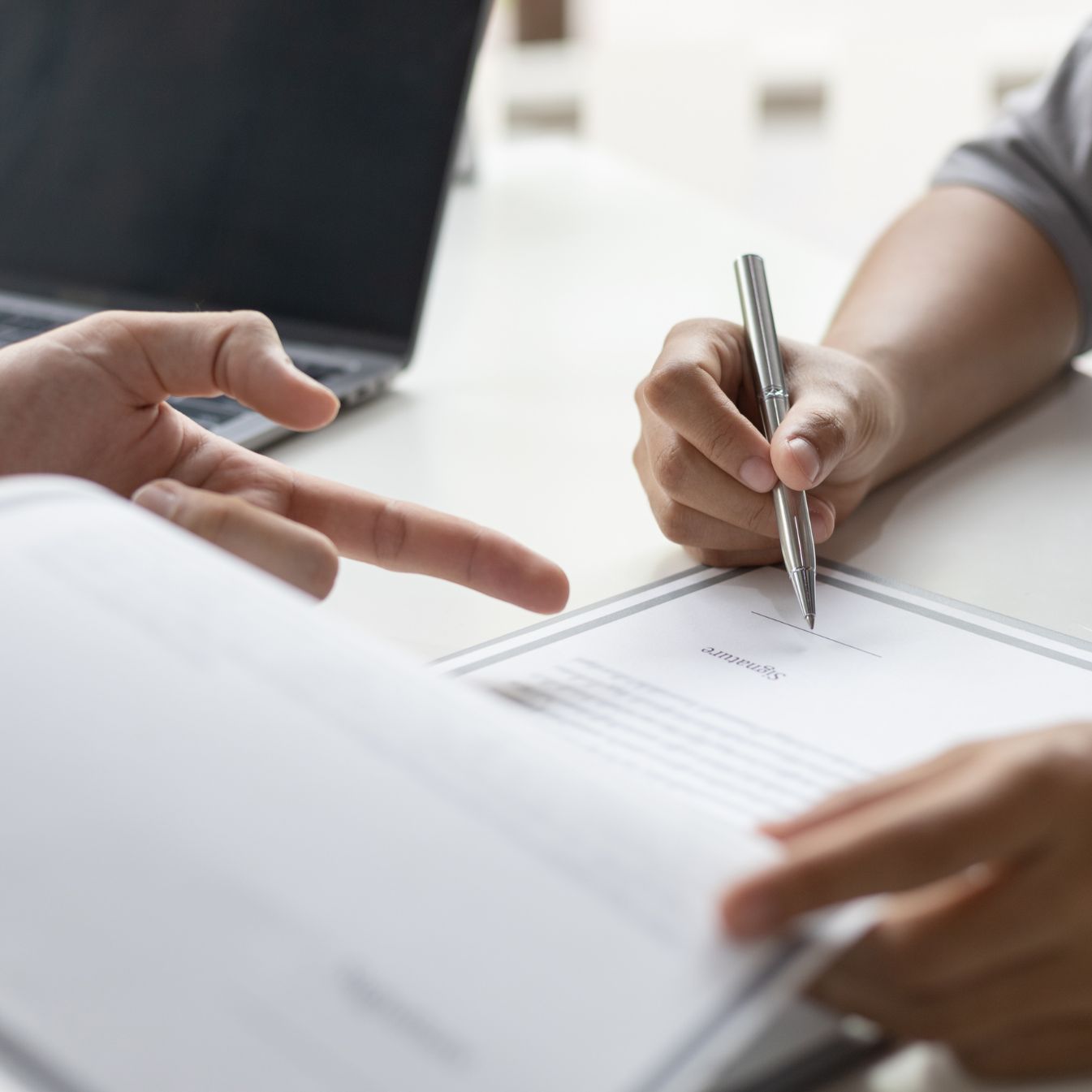 Gros plan sur une signature de contrat entre deux personnes, symbolisant la finalisation des premiers accords de franchise.