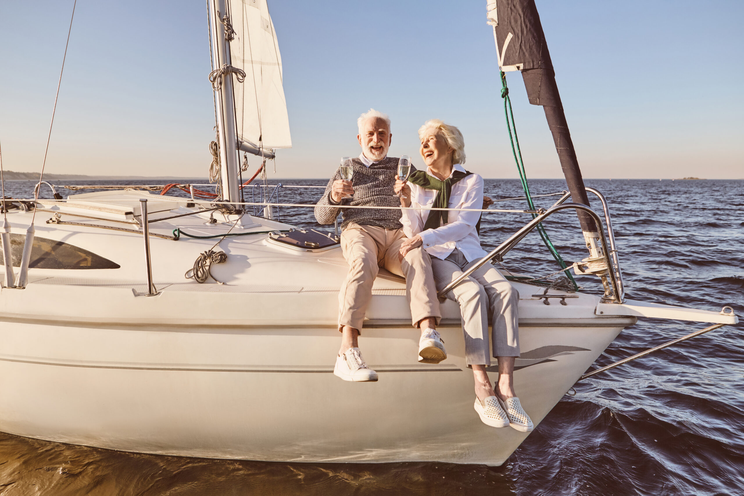 Couple senior souriant profitant d’une sortie en voilier, symbole d’une retraite sereine et confortable.