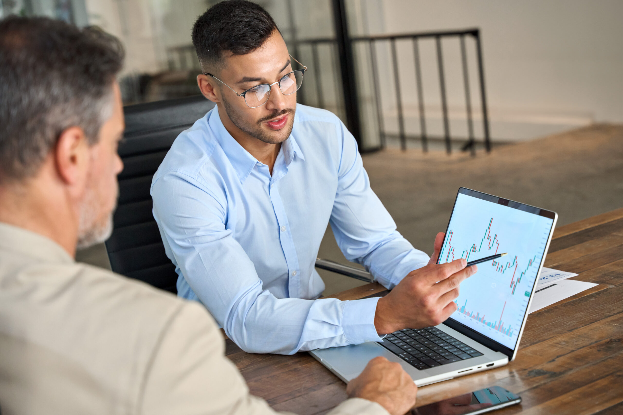 Conseiller en gestion de patrimoine présentant une stratégie d’investissement à son client sur un ordinateur.
