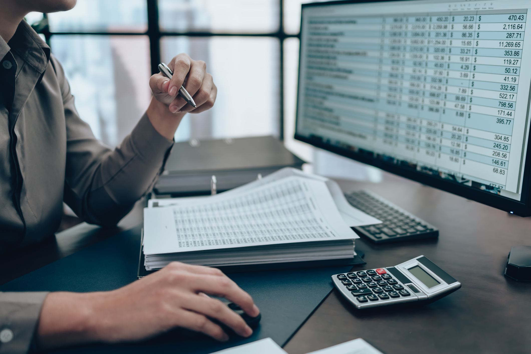 Un expert-comptable vérifie des documents financiers et des écritures comptables à l’écran dans le cadre d’une tenue et révision comptable.
