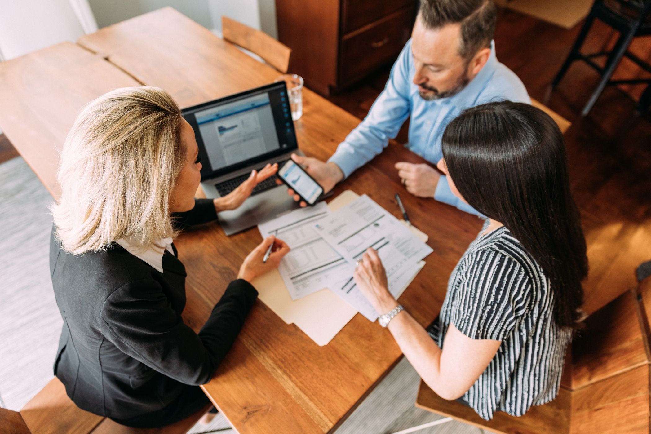 Consultation patrimoniale : un conseiller analyse la situation financière d’un couple autour de documents et d’un ordinateur.