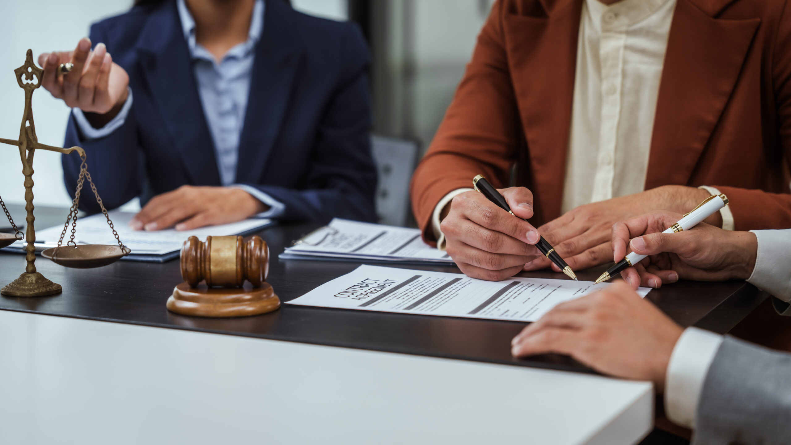 Réunion juridique : avocats et clients signant des documents liés à une opération patrimoniale avancée.